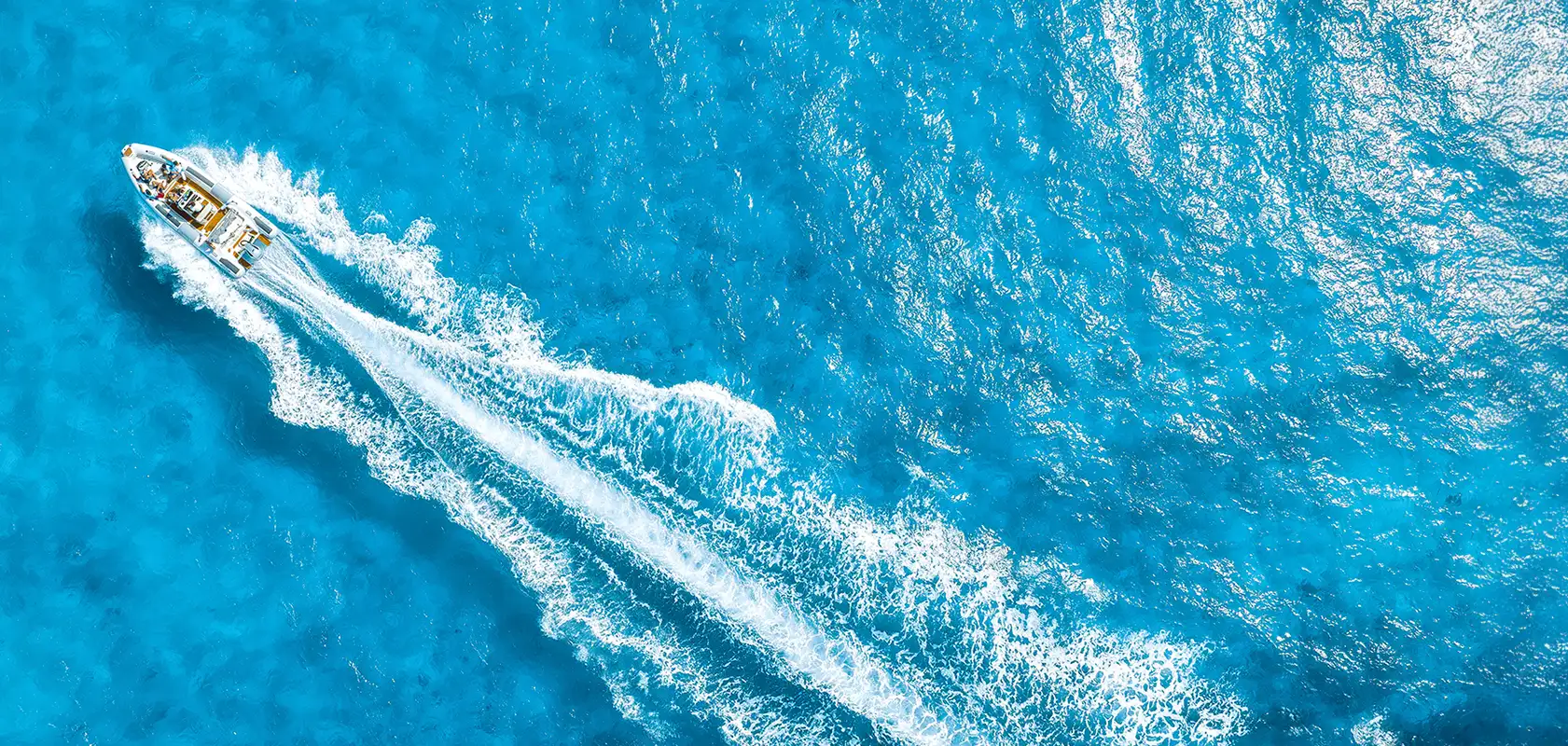 Aerial view of boat cutting through crystal blue water