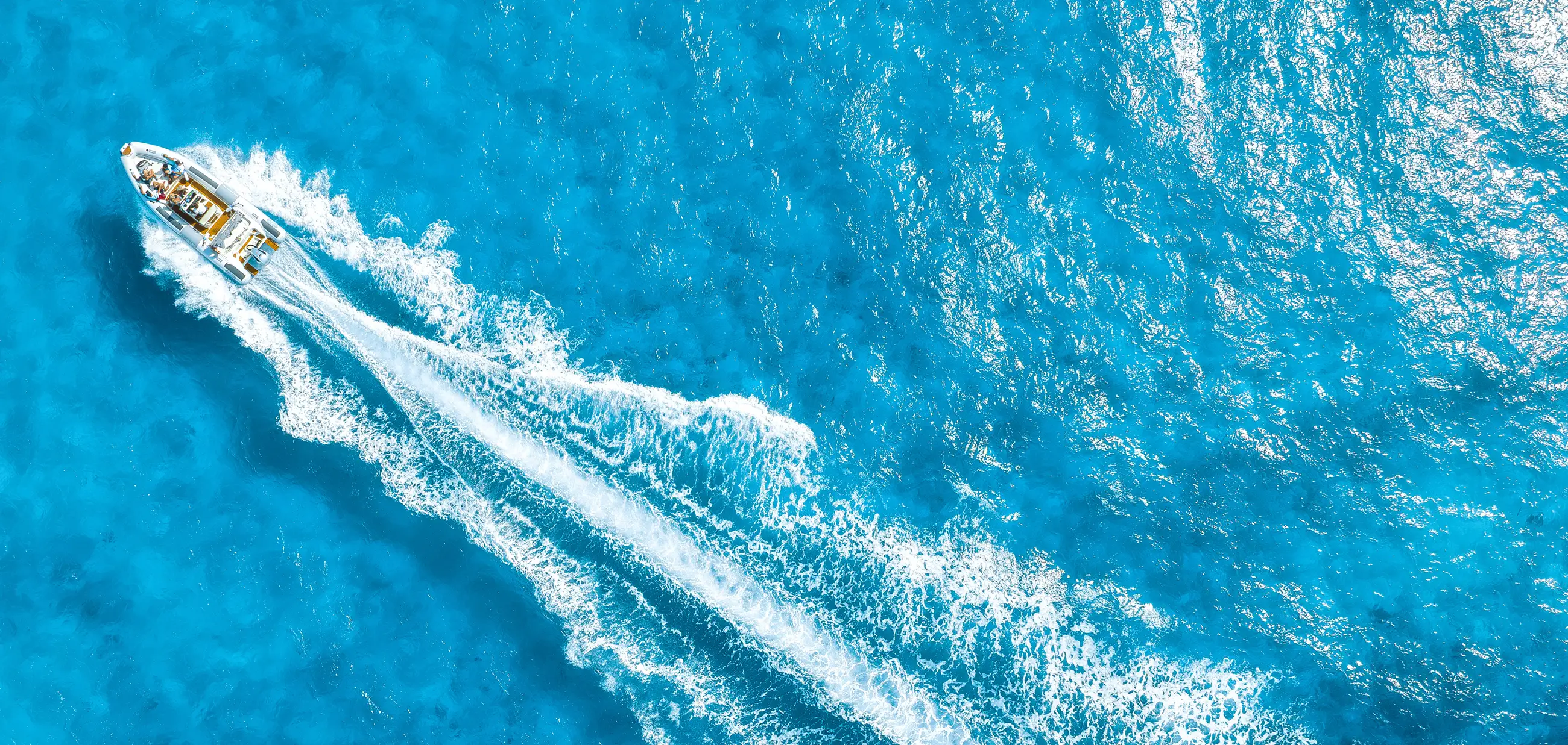 Aerial view of a boat rental cruising through clear blue water in Miami